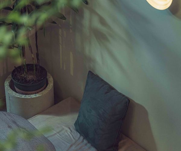 Cozy yoga corner at home with a mat, cushions, a plant, and soft ambient light.