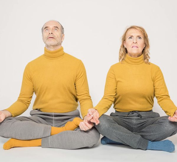 Person smiling peacefully while sitting on a yoga mat, embodying a sense of well-being.